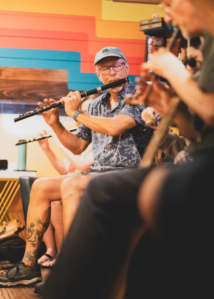 Man playing a flute during a traditional Irish session